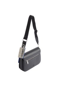 Szara skórzana torebka na ramię z klapką, przednią kieszenią na zamek błyskawiczny oraz regulowanym czarnym paskiem. Zawiera dekoracyjną zawieszkę z wzorem.