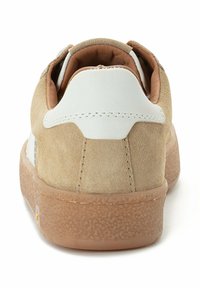 Beige Wildledersneaker mit einer weißen Leder-Hinterkappe, strukturiertem Gummisohle und gesteppten Details am oberen Rücken und an den Seiten.