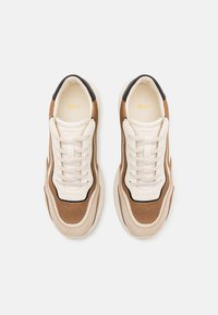 Bruna och beige sneakers med en mesh-överkonstruktion, vadderad tunga och gummisula. Svarta accenter längs kanterna och logotyp på tungan.