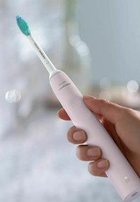Philips Sonicare elektrische tandenborstel, met een slanke witte handgreep, roze accenten en een blauwe en groene borstelkop. De aan/uit-knop is zichtbaar.