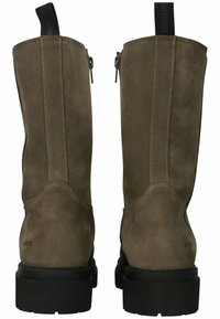 Botas de tobillo de ante marrón con un acabado mate, suela de goma negra, cremalleras laterales y una lengüeta en la parte posterior para ponerse fácilmente.