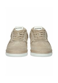 Pari beigeä mokkanahkaisia Blackstone-tennareita valkoisilla pohjilla, etunäkymä, jossa näkyvät nauhat ja merkkikilvet kielekkeissä.