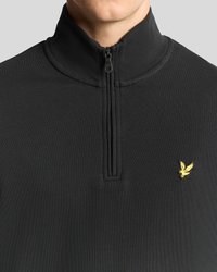 Juodas zip-up puloveris, pagamintas iš raukšlėtos medžiagos su glotnia tekstūra. Ant kairiojo krūtinės yra mažas geltonos paukščio logotipas.