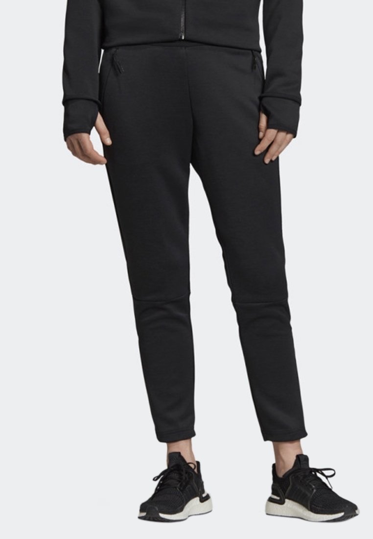Svarta joggingbyxor med smal passform, med diskreta knäpaneler och fickor med dragkedja. Matchas med svarta löparskor.
