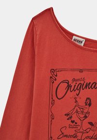 Rotes Baumwollhemd mit langen Ärmeln, das ein retro Grafikdesign einer Frau mit einem Cocktail und einem weiten Ausschnitt für eine lässige Passform zeigt.