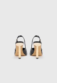 Pantofi cu toc slingback din piele lăcuită neagră, cu un toc geometric, în formă de bloc, de culoare aurie. Textură netedă și design minimalistic fără elemente decorative suplimentare.