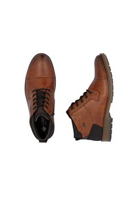 Bottines en cuir marron avec un bout arrondi, des accents noirs et une semelle marron contrastante. Elles sont dotées de lacets et d'un panneau texturé au niveau de la cheville.
