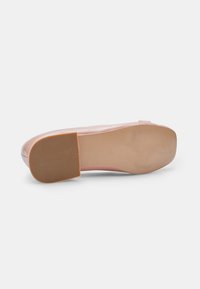 Pantof în nuanță de roz, cu o finisare netedă și lucioasă, talpă din cauciuc cu un grip texturat și un design al vârfului ușor rotunjit.