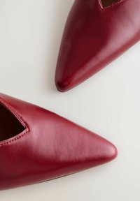 Spitze Schuhe aus glänzendem burgunderfarbenem Leder mit einem Ausschnitt. Glatte Textur und eleganter Schnitt, mit einem minimalistischen Design.