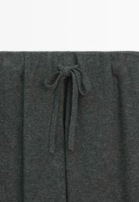 Donkergrijze gebreide stof broek met een elastische tailleband en een getrokken koord in het midden van de voorkant.