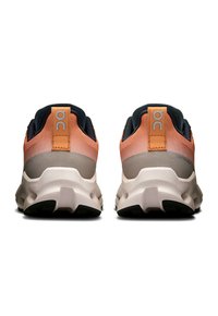 Vista posteriore di scarpe da ginnastica atletiche con tomaia in mesh arancione e grigia, colletto imbottito e suola intermedia bianca con suola nera testurizzata.