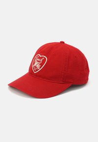 Casquette de baseball rouge en tissu coton, ornée d'un patch brodé blanc en forme de cœur avec le mot "Coach" et un design ailé.