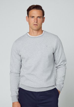 Ljusgrå sweatshirt med rund hals och långa ärmar, med en diskret logotyp på bröstet och ribbade muddar och nederkant.