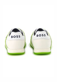 Witte en groene sneakers met een textuur rubberen zool, voorzien van een logo op de hiel. Het ontwerp bevat contrasterende marineblauwe accenten.