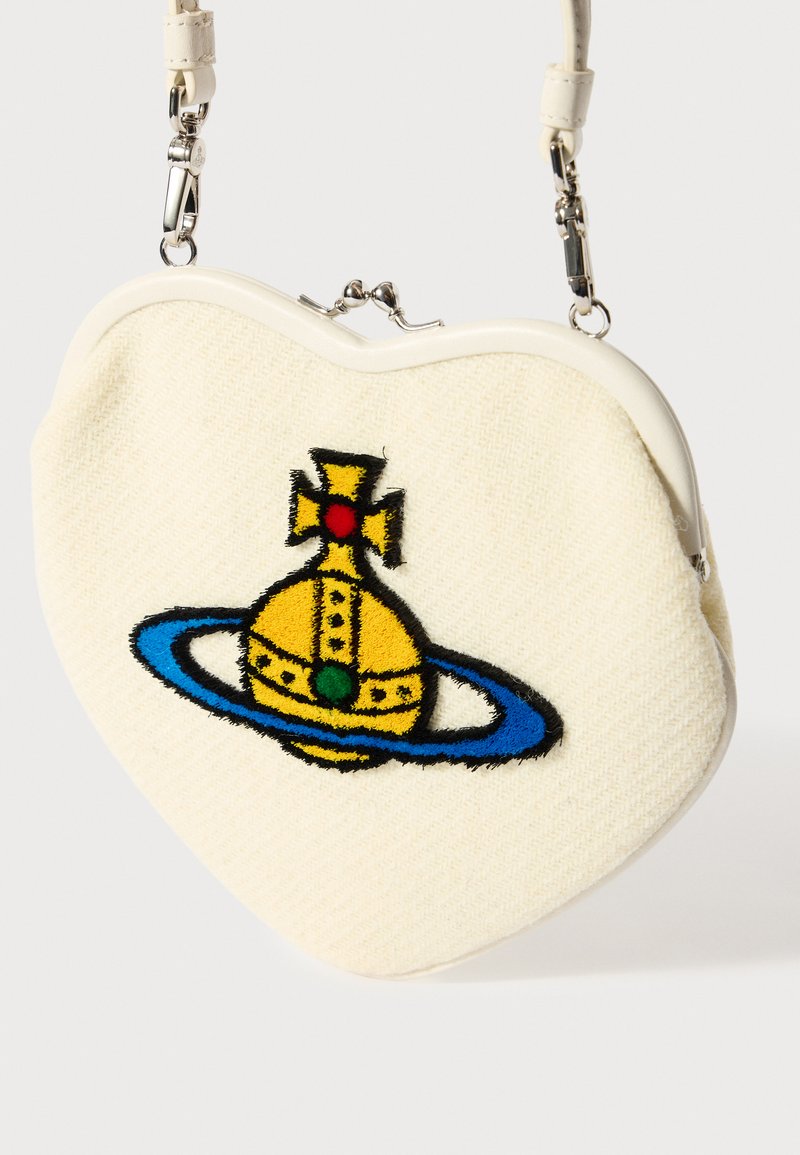Bolso en forma de corazón hecho de tela crema. Presenta un diseño de corona bordado en colores amarillo, verde y rojo, con un anillo de acento azul.