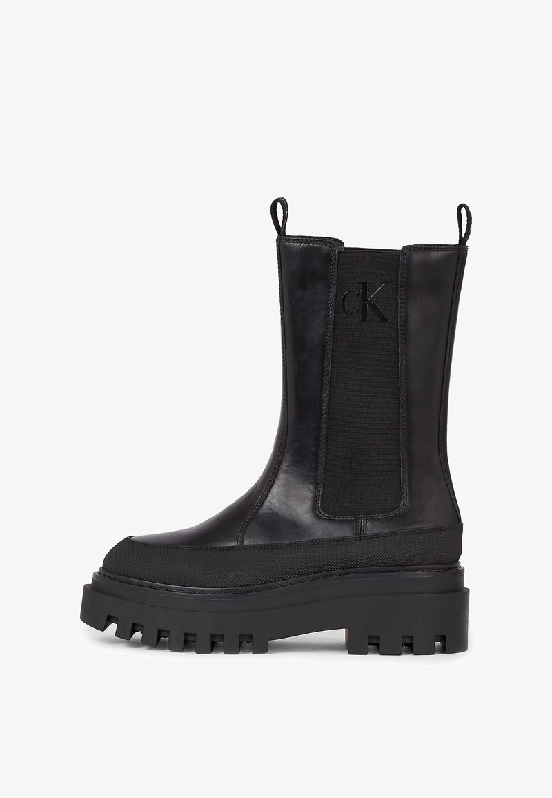 Black leather ankle boots with elastic side panels, chunky rubber sole, and a round toe. Includes customer-embossed logo on the side.