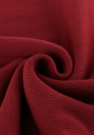 Tessuto a maglia bordeaux con una texture liscia, caratterizzato da un'intrecciatura delicata e uniforme e una leggera elasticità, drappeggiato in morbidi strati.