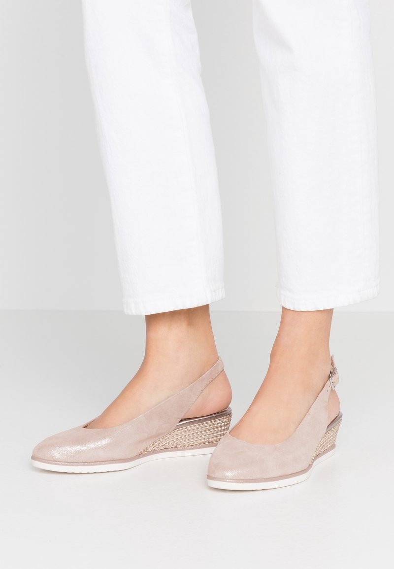 Beige wedge sandaaltjes met een suède bovenkant, open teen en slingback ontwerp. Beschikt over een gestructureerde geweven hak en een gladde witte zool.