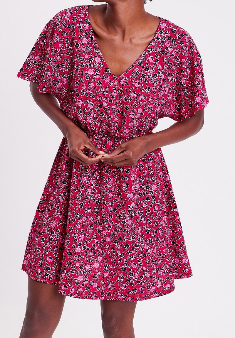 Floral dress in pink with black and white accents. V-neckline, short flutter sleeves, cinched waist, and knee-length skirt. Lightweight fabric.