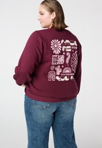 Bordeauxrode sweater met een grafisch ontwerp in lichtroze, met bloemmotieven en speelse patronen op de achterkant. Losse pasvorm, gemaakt van een katoenmengsel.