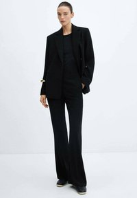 Black tailored blazer and fitted black pants in a smooth fabric. The suit features a double-breasted design and flared pant legs.