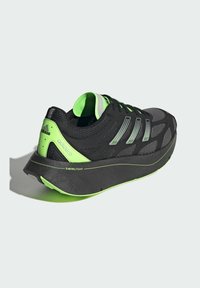 Čierne športové topánky so zelenými akcentmi, ktoré majú sieťovanú vrchnú časť, vyplnenú hrubou podrážkou označenou "SWIRLFOAM", a tromi reflexnými pruhmi.