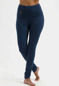 Dunkelblaue Leggings mit einem breiten, strukturierten Taillenbund und figurbetontem Design. Dezenter Neonorange-Logoakzent am waistband. Weicher Stoff.