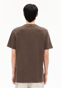 Braunes Baumwoll-T-Shirt mit kurzen Ärmeln und Rundhalsausschnitt. Der Stoff hat eine leicht strukturierte Oberfläche, und die Rückseite ist schlicht ohne Grafiken.