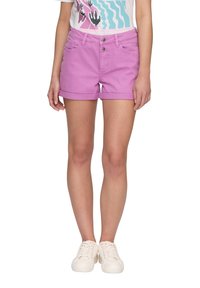 Shorts en denim rose avec des revers roulés, deux poches avant et une fermeture à boutons. Associés à un t-shirt à imprimé graphique et des baskets blanches.