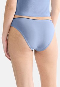 Jasnoniebieskie bawełniane bikini o gładkiej fakturze, niskim kroju i kontrastowym ciemnym pasku.