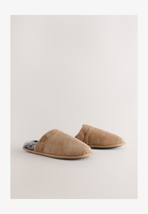 Pantofole in tessuto intrecciato color nocciola con esterno strutturato, interno morbido grigio e suola piatta in gomma. Il design presenta uno stile senza lacci.