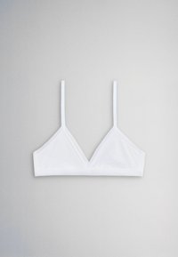 Biely minimalistický trojuholníkový bralet s tenkými nastaviteľnými ramienkami položený na svetlošedom pozadí.