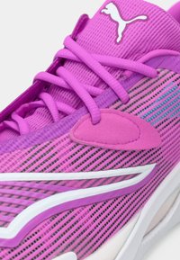 Tuva skatā violetas Puma skriešanas kurpes ar tīkla audumu, saskaņotām šņorēm, baltu Puma logotipu uz mēles un baltu un violetu sānu svītru.