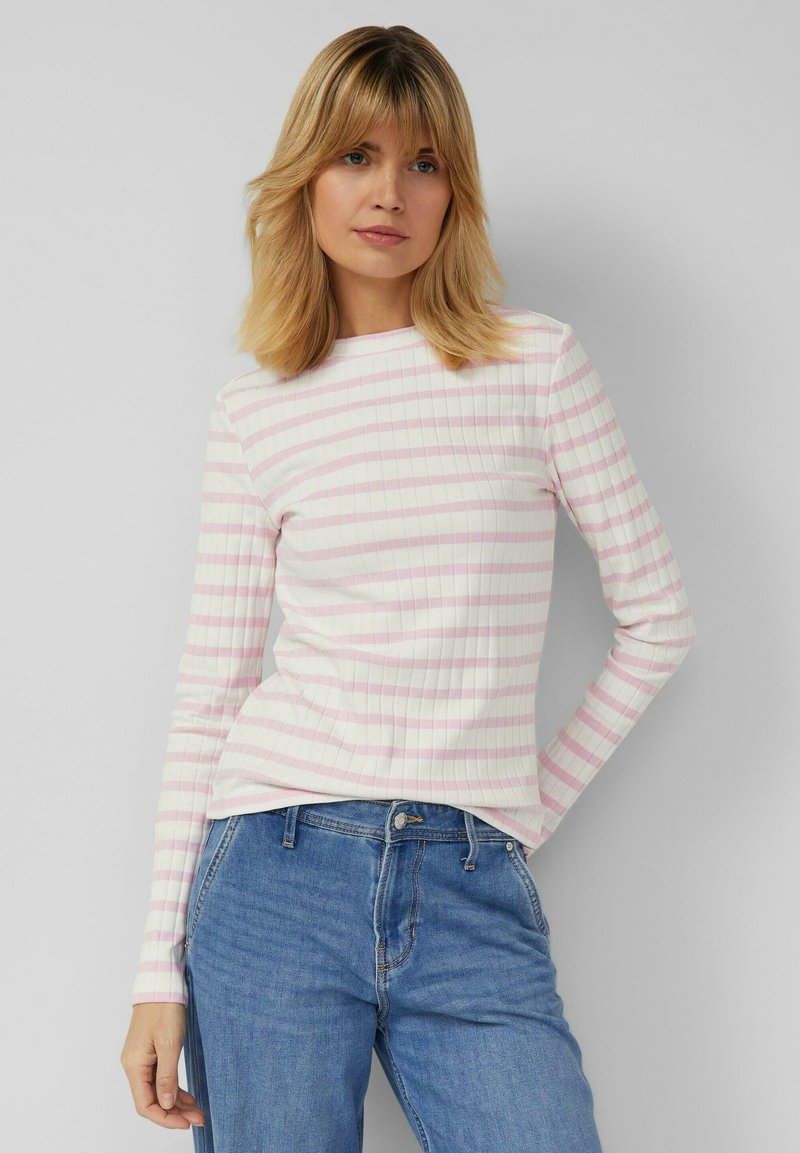 Long-sleeve ribbed top in white with light pink horizontal stripes. Features a round neckline and a fitted shape. Paired with blue jeans.