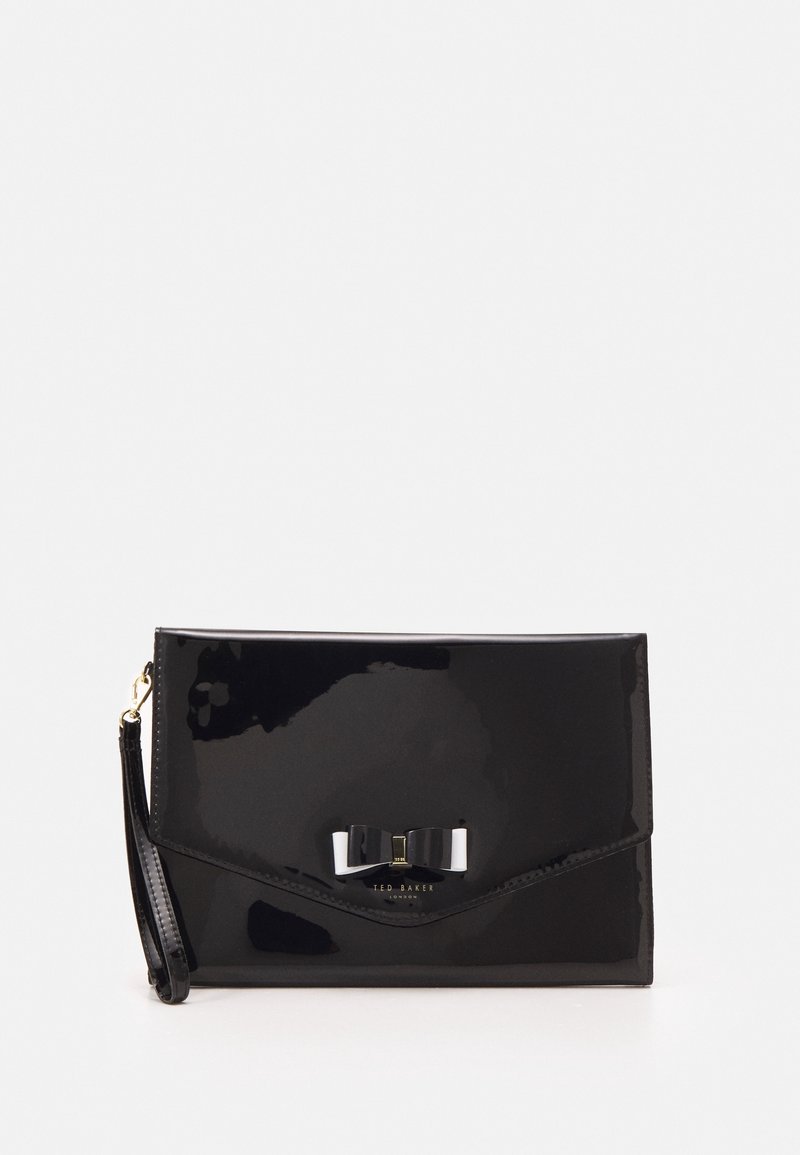 Černá lakovaná kabelka s lesklým povrchem, s ozdobou ve tvaru mašle a hardwarem ve zlatém tónu. Obsahuje odnímatelný zápěstní pásek.