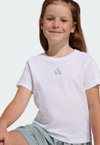 White cotton t-shirt featuring a small grey Adidas logo on the chest. Short sleeves, crew neck, smooth texture, suitable for casual wear.