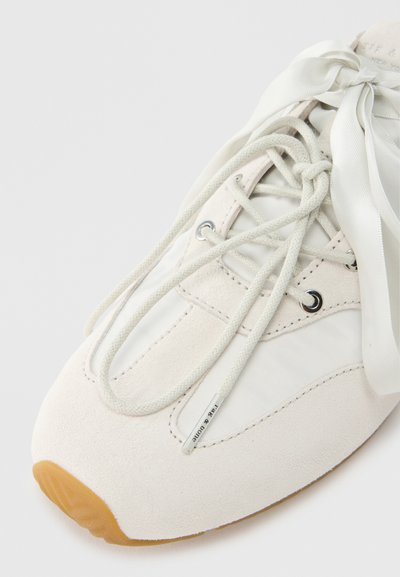 Hvide sneakers med overdel i ruskind og tekstilpaneler, rund tå, flade snørebånd fastgjort med sølvfarvede snørehuller og en sål i gummigummi.