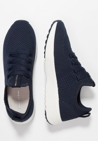Granatowe siatkowe sneakersy z zaokrąglonym noskiem, białą gumową podeszwą i dopasowanymi sznurówkami. Posiadają pętlę na pięcie, ułatwiającą zakładanie.