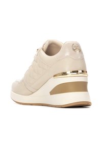 Las zapatillas tipo cuña de color beige presentan un acabado acolchado, acentos de cuero patente brillante, herrajes dorados y una suela texturada para mayor tracción.