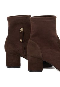 Pair of brown suede ankle boots with block heels and gold zipper details on the inner side of each boot.