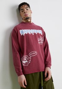 Maroon langermet t-skjorte med hvite grafiske design, inkludert tegneseriefigurer og tekst. Laget av myk bomull.