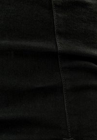 Černá denimová tkanina s hladkou strukturou, s švy podél lemů a jemným diagonálním vzorem tkaní.