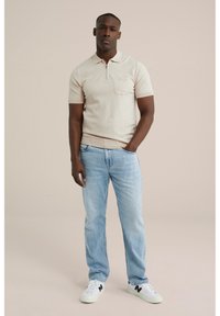 Beige knit polo shirt with a zip collar and chest pocket, paired with light blue jeans and white sneakers featuring black accents.