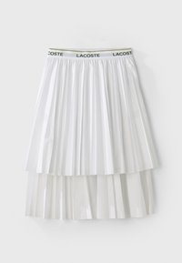 Hvit plissert skjørt med en teksturert design, som har en merkebånd i elastisk midje. Materialet har en jevn overflate med lagdelte segmenter.