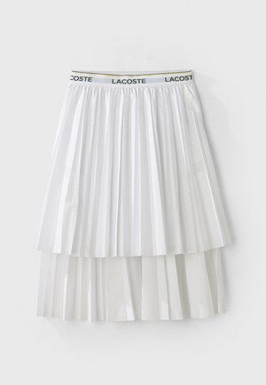 Biela skladaná sukňa s textúrovaným dizajnom, vybavená elastickým opaskom s logom. Materiál má hladký povrch s vrstvenými segmentmi.