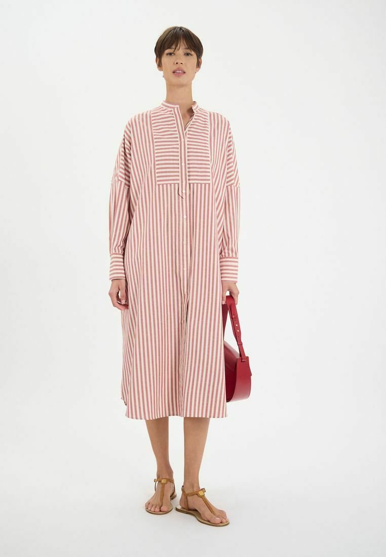 Robe midi rayée en tissu doux, dotée d'un devant à boutons, d'un col, de manches tombantes et d'une coupe droite. Portée avec un sac rouge et des sandales.