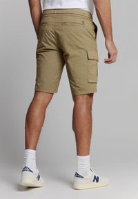 Khaki cargoshorts met achterzakken, zijcargo zakken, rechte snit, katoen stof en casual ontwerp. Draagt met witte sokken en schoenen.