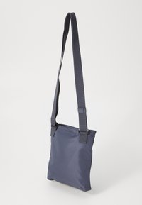 Borsa a tracolla in nylon navy con design piatto, cinturino regolabile in tessuto e chiusura con zip. Texture liscia con una leggera lucentezza.