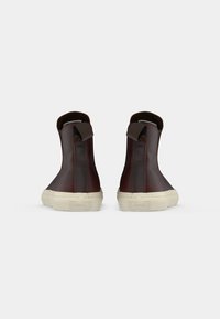 Hnědé kožené kotníkové boty s hladkým povrchem, nízkým podpatkem, béžovou gumovou podrážkou a zadním poutkem pro snadné obutí.