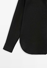 Zwarte blouse met lange mouwen, knoopsluiting, zichtbare manchetten en afgeronde zoom op een witte achtergrond.